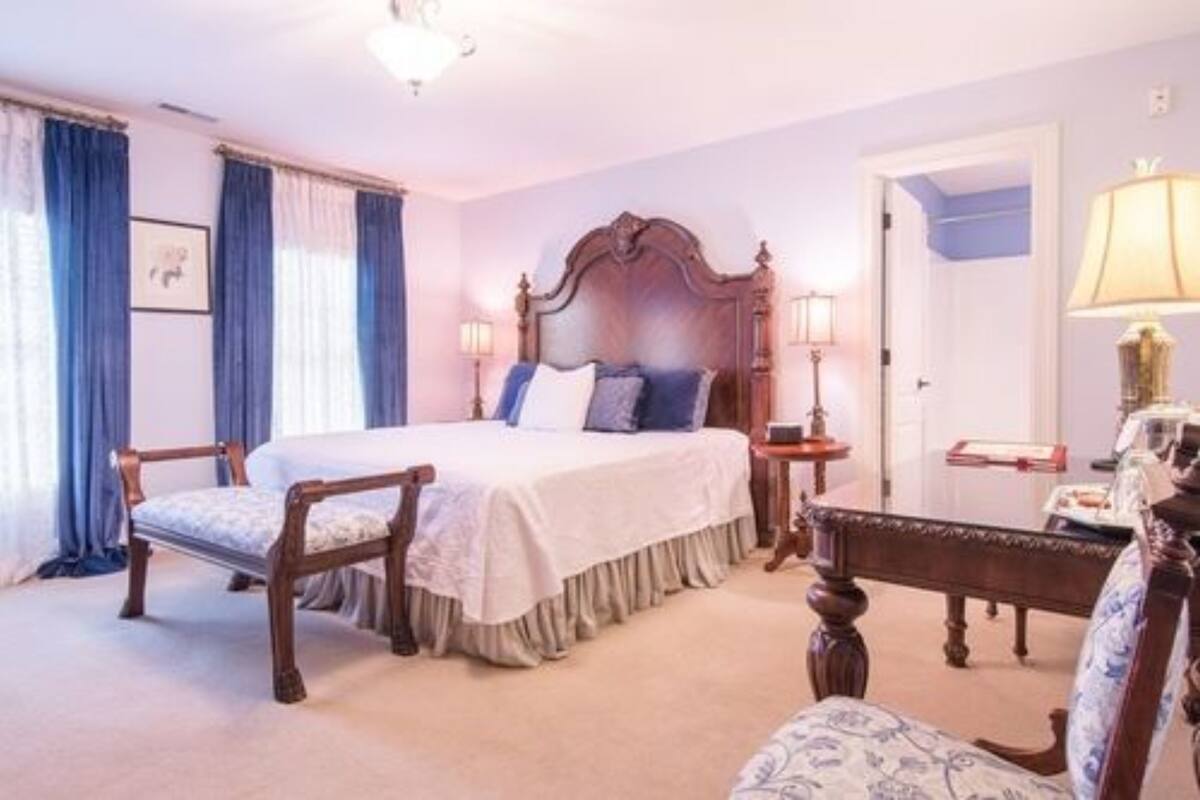 A bedroom with a large bed, two bedside tables, a chair, and a desk.