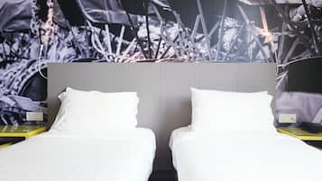A hotel room with two single beds, a grey headboard, and a large abstract mural on the wall.