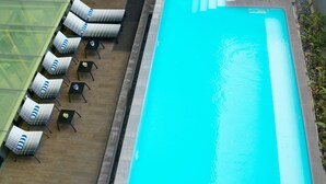 A swimming pool with lounge chairs and tables, a tiled deck, and a stone wall. - Travelodge Georgetown (George Town)