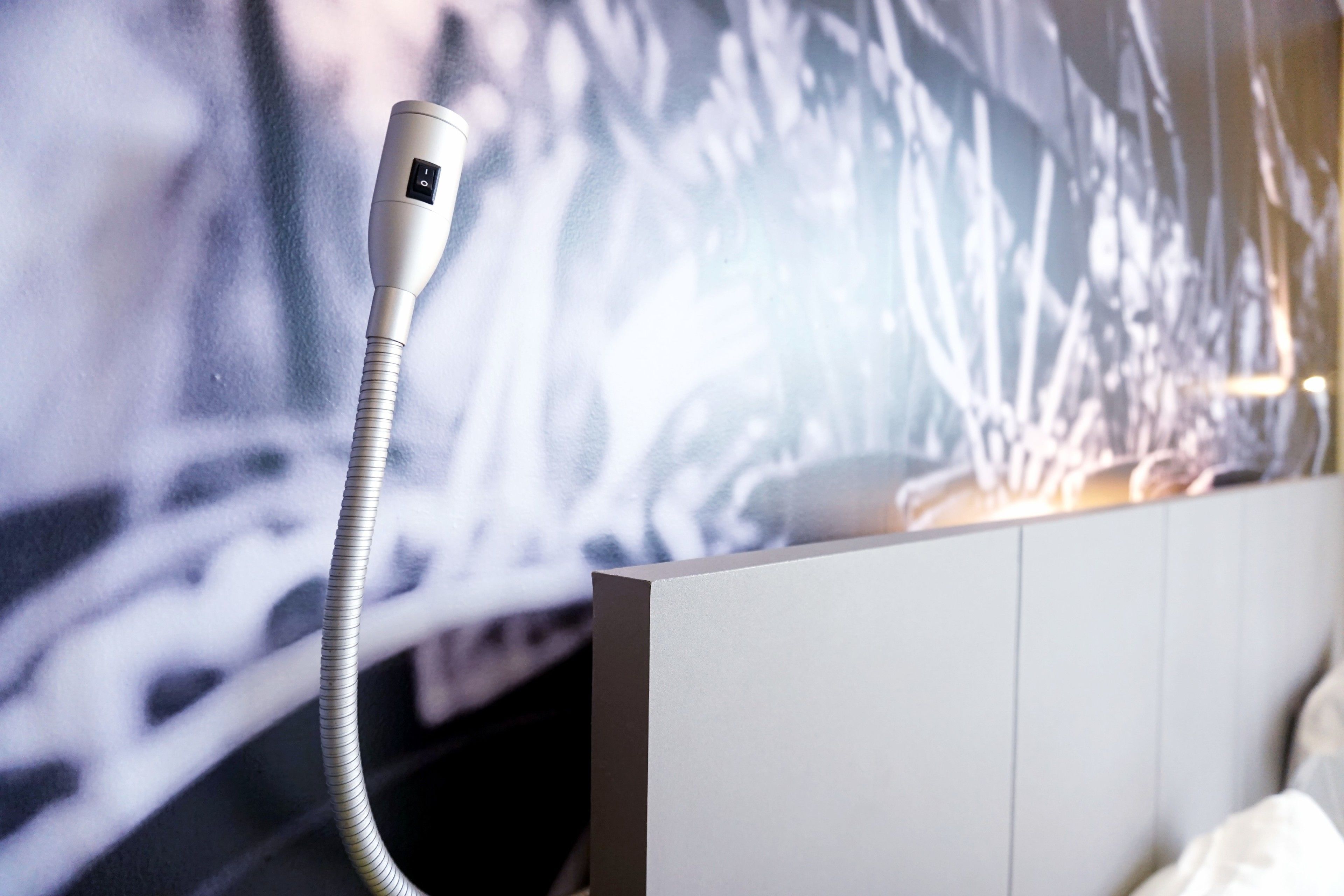 A room with a bed, a white headboard, and a wall-mounted air purifier.