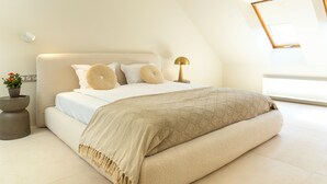 Un dormitorio moderno con una cama grande, una mesita de noche, una lámpara y una ventana.