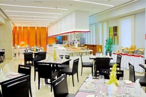 Guests can dine in style with tables set with white tablecloths and black chairs, surrounded by festive decorations and vertical panels.