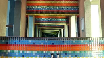 A bathroom with two sinks, colorful mosaic tiles on the walls, and a mirror reflecting the space.
