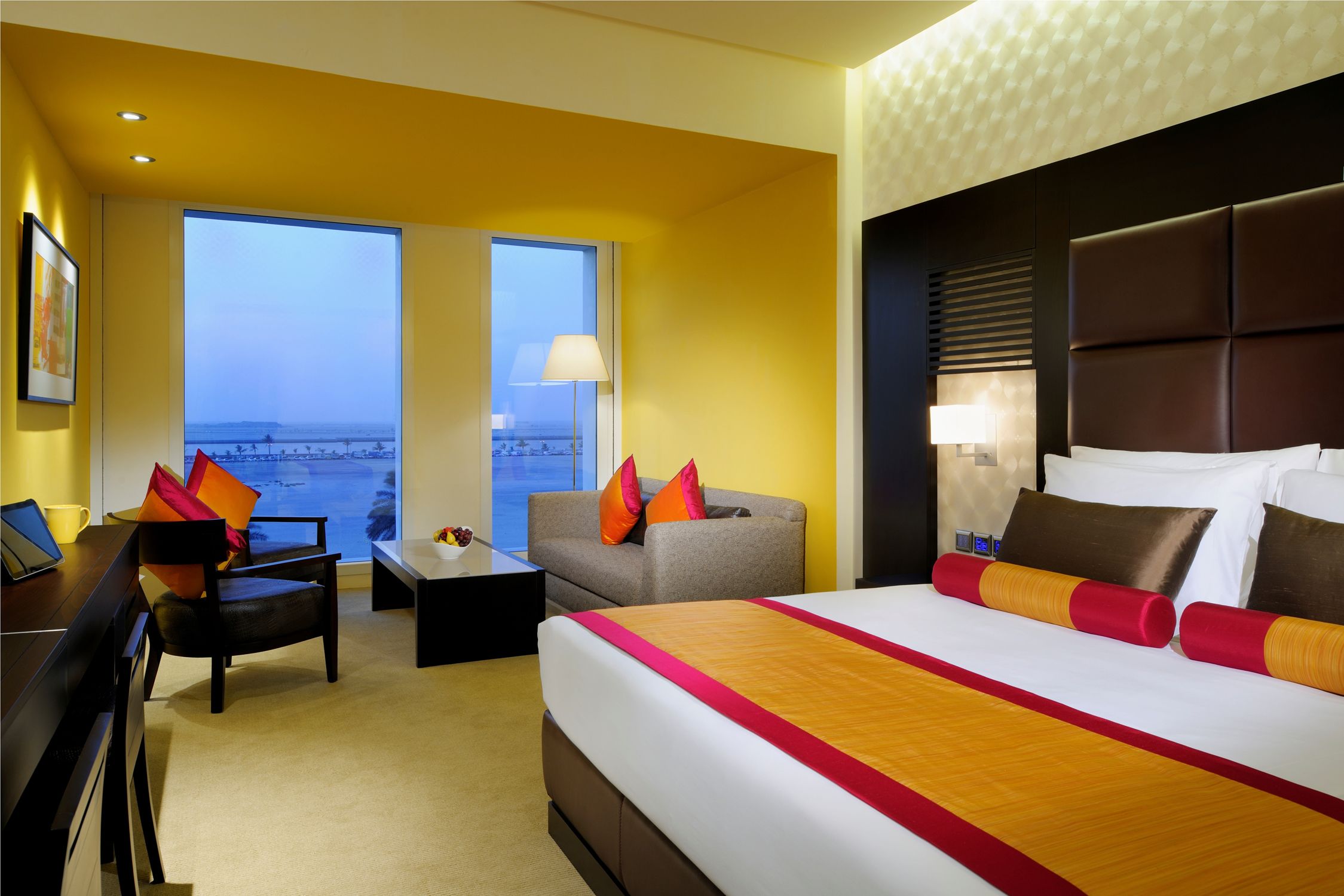 Quarto de hotel com uma cama grande, uma escrivaninha, uma cadeira e vista para a cidade.