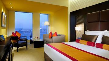 Quarto de hotel com uma cama grande, uma escrivaninha, uma cadeira e vista para a cidade.