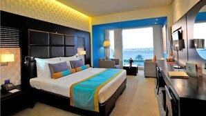 Una habitación de hotel moderna con una cama grande, un escritorio y vista al mar.