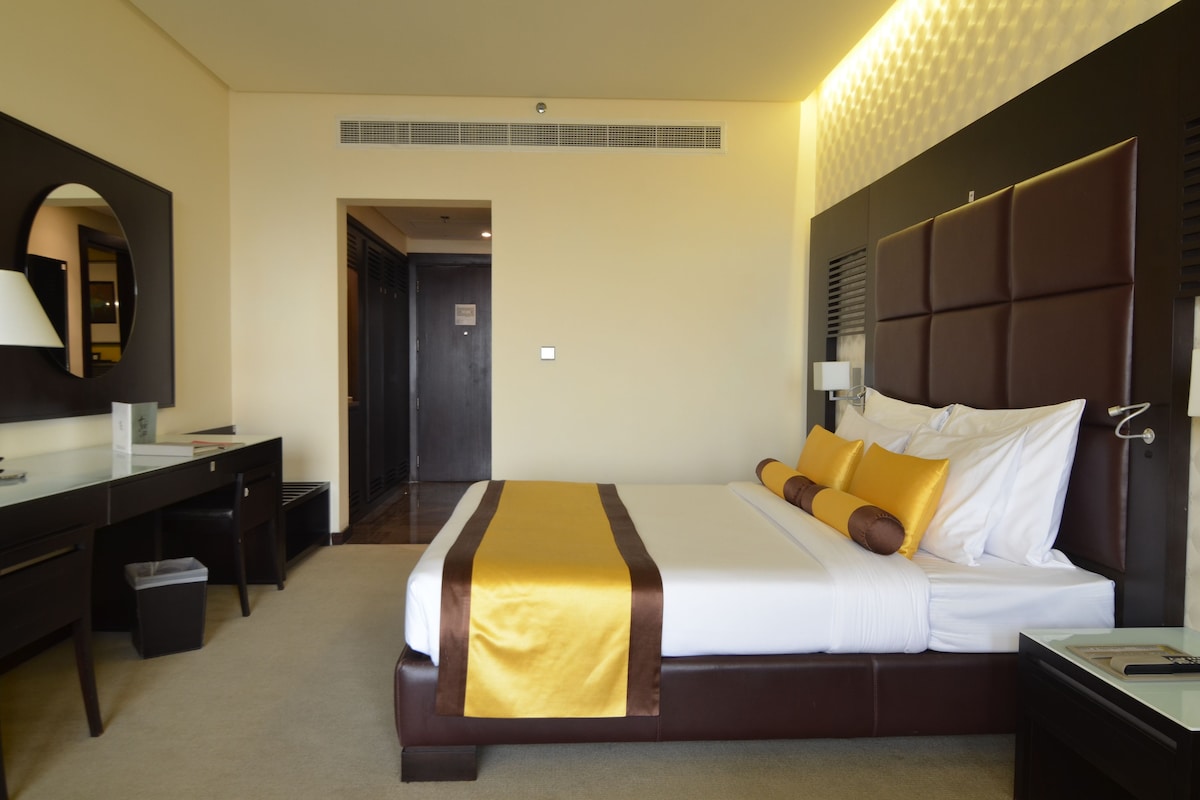 Habitación de hotel con una cama grande, un escritorio, una silla y un espejo.
