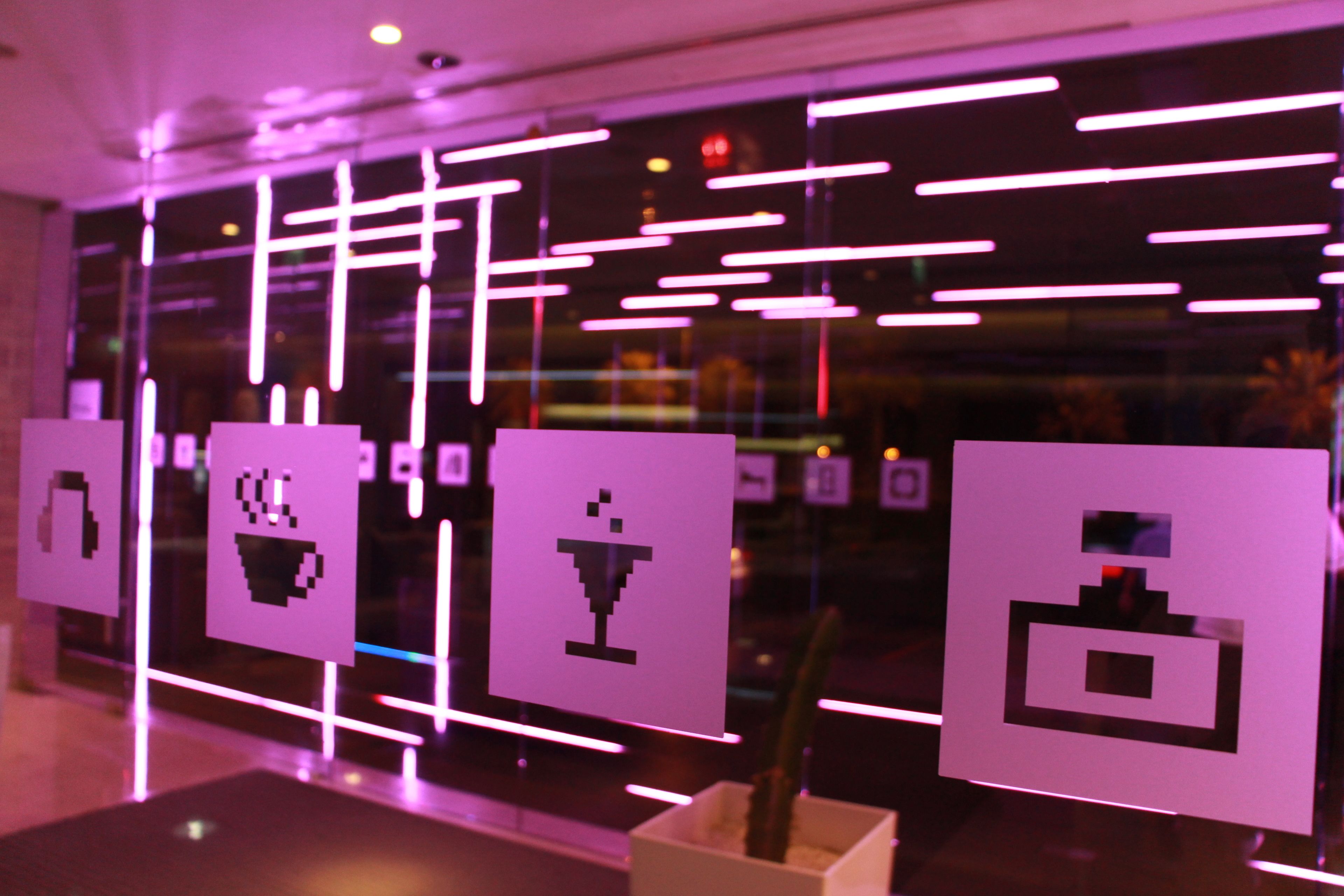 A modern interior with illuminated signs displaying icons for amenities like a bed, a cup, and a wine glass.