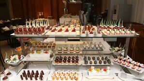 Un bufé con diversos postres y bocadillos dispuestos en varias vitrinas de vidrio.