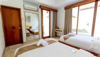 Una camera d'albergo con due letti, una scrivania, uno specchio e una porta.