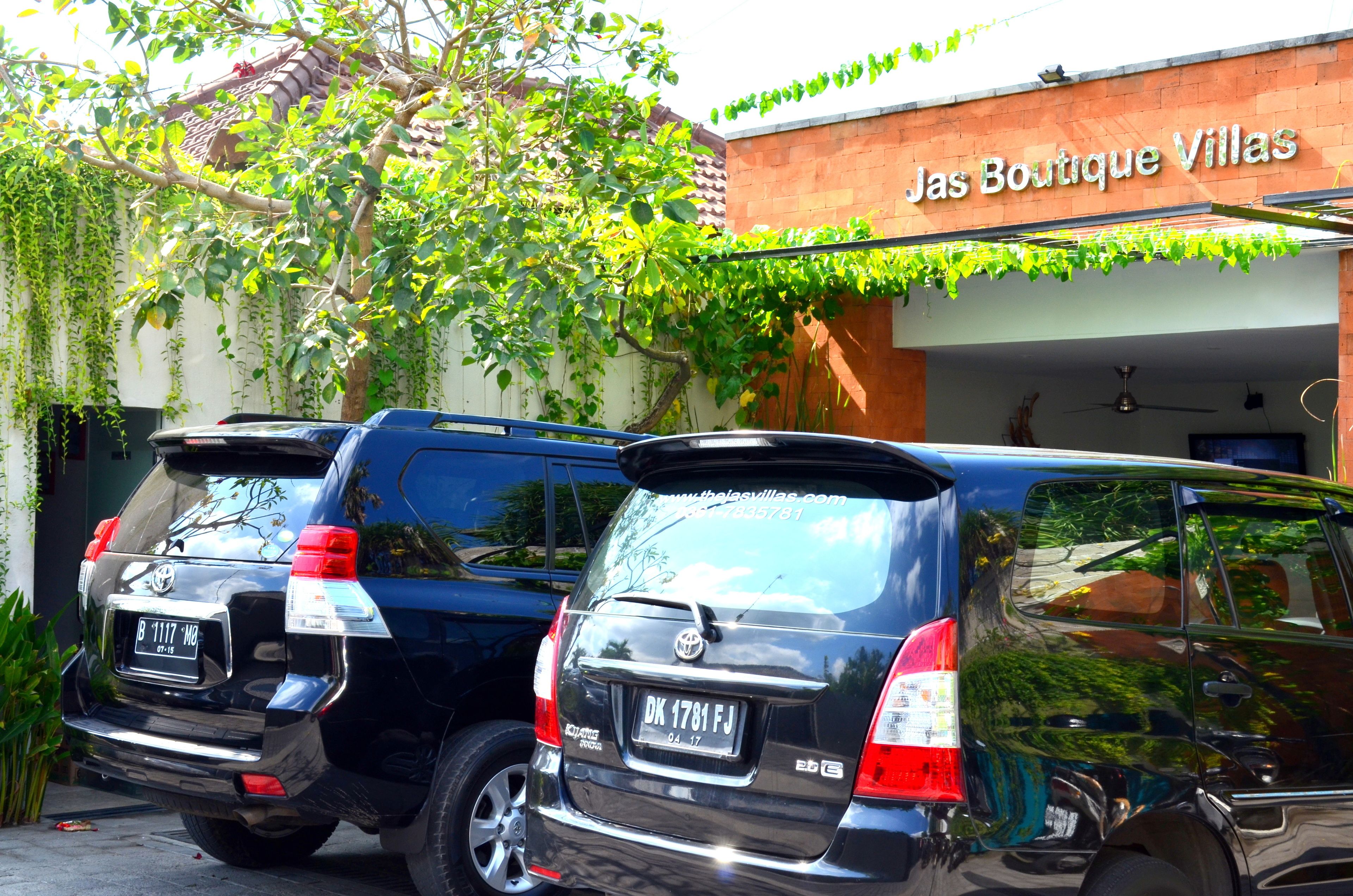 Dos SUVs negros estacionados frente a un edificio con un letrero que dice 'Jas Boutique Villas'.