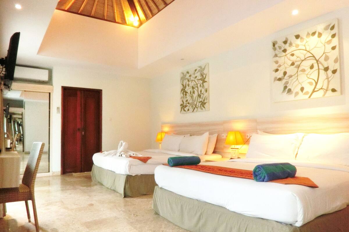 A hotel room with two beds, a desk, and a chair.