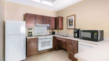 A compact kitchen with a refrigerator, stove, microwave, and sink.
