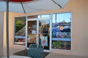 A cafe with a glass door, outdoor seating, and a menu board advertising pastries, coffee, and ice cream.