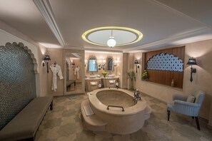 Een luxe badkamer met een vrijstaand bad, een wastafel met meerdere wasbakken en een grote spiegel.