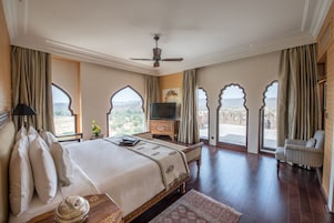 A spacious bedroom with a large bed, a television, and a view of the outdoors.