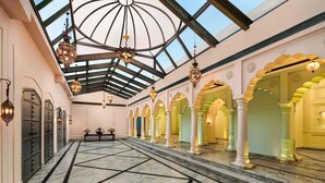 A spacious hall with a high ceiling and skylight, featuring a marble floor and ornate columns. - Fairmont Jaipur (Amer)