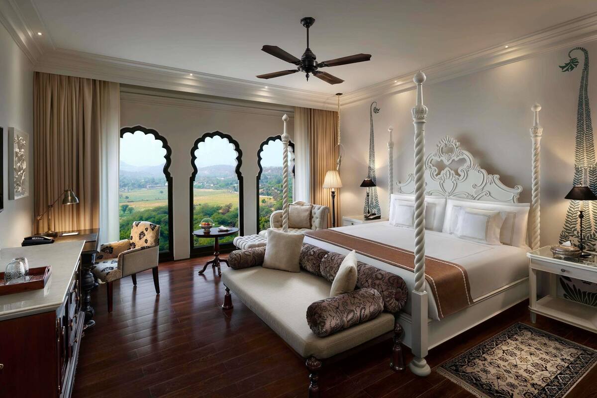 Ein geräumiges Schlafzimmer mit einem großen Bett, einer Sitzecke und Blick auf die Landschaft.
