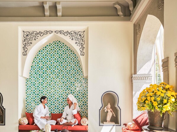 A room with a red sofa, a decorative archway, and a statue.