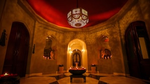 A lobby with a checkered floor, a central fountain, and a red ceiling. - Fairmont Jaipur (Amer)