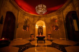 A lobby with a checkered floor, a central fountain, and a red ceiling.