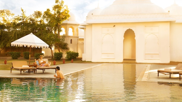 A pool area with lounge chairs and a building with domed architecture. - Fairmont Jaipur (Amer)
