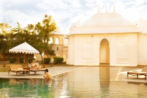 A pool area with lounge chairs and a building with domed architecture.