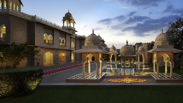 A grand building with multiple domes and arches, a courtyard with a fountain, and a red carpet path. - Fairmont Jaipur (Amer)