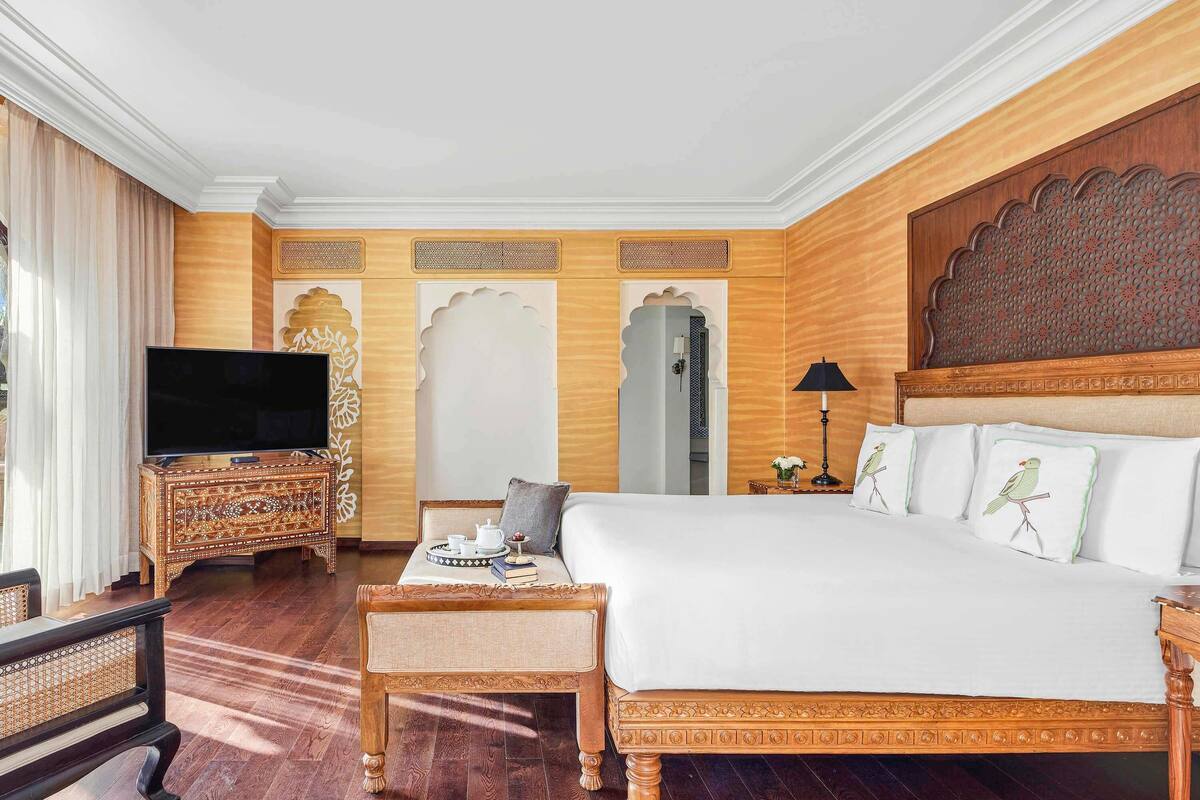 Ein Hotelzimmer mit einem großen Bett, einem Fernseher, einem Holzschrank und einer dekorativen Wandverkleidung.