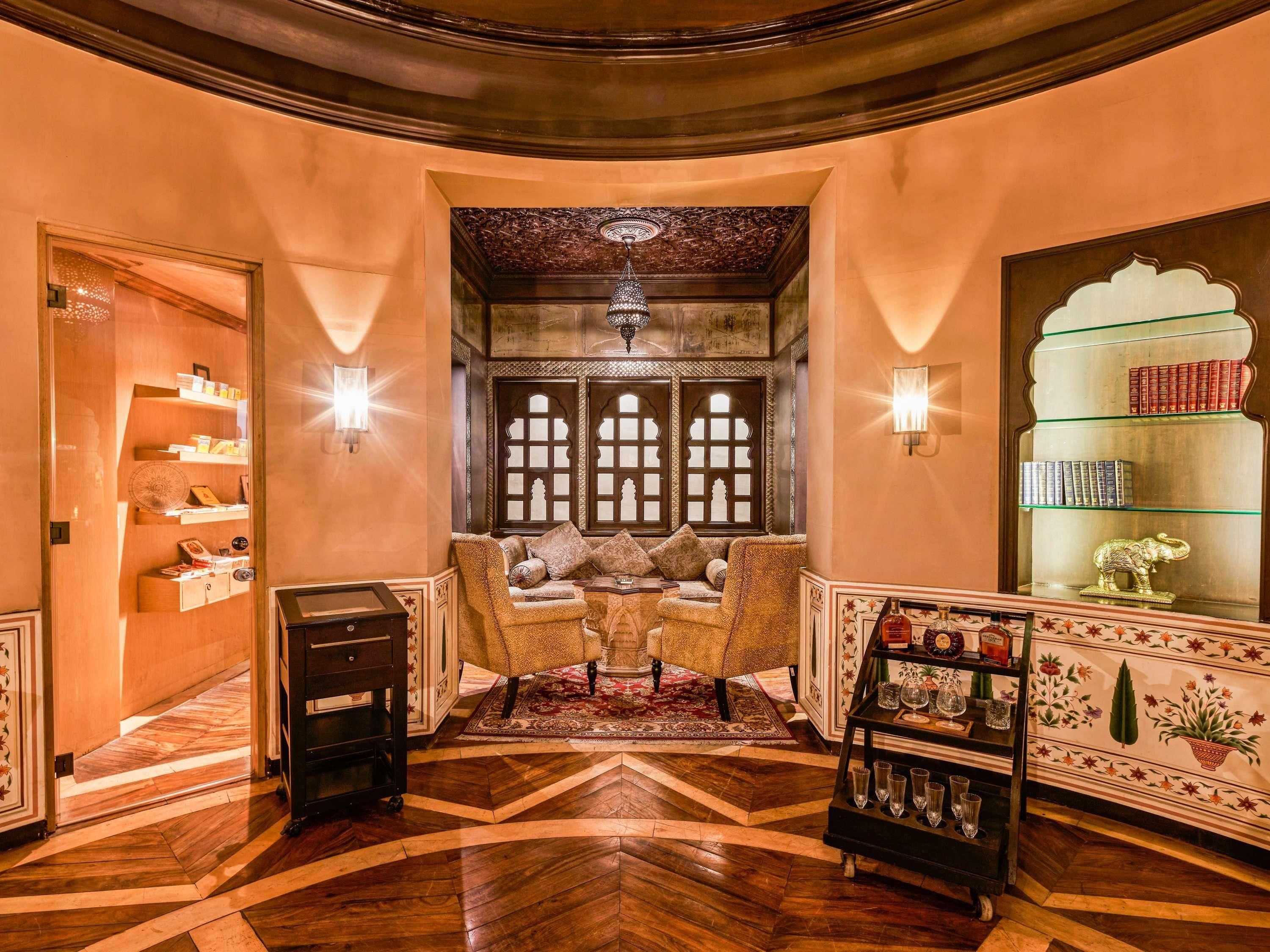 Um interior tradicional com um sofá, um armário de madeira cheio de livros e uma estante decorativa com copos.
