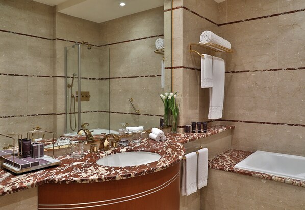 Un baño con tocador de mármol, un espejo grande, cabina de ducha de vidrio y una bañera.