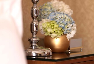 A gold vase with blue and white flowers on a reflective surface.