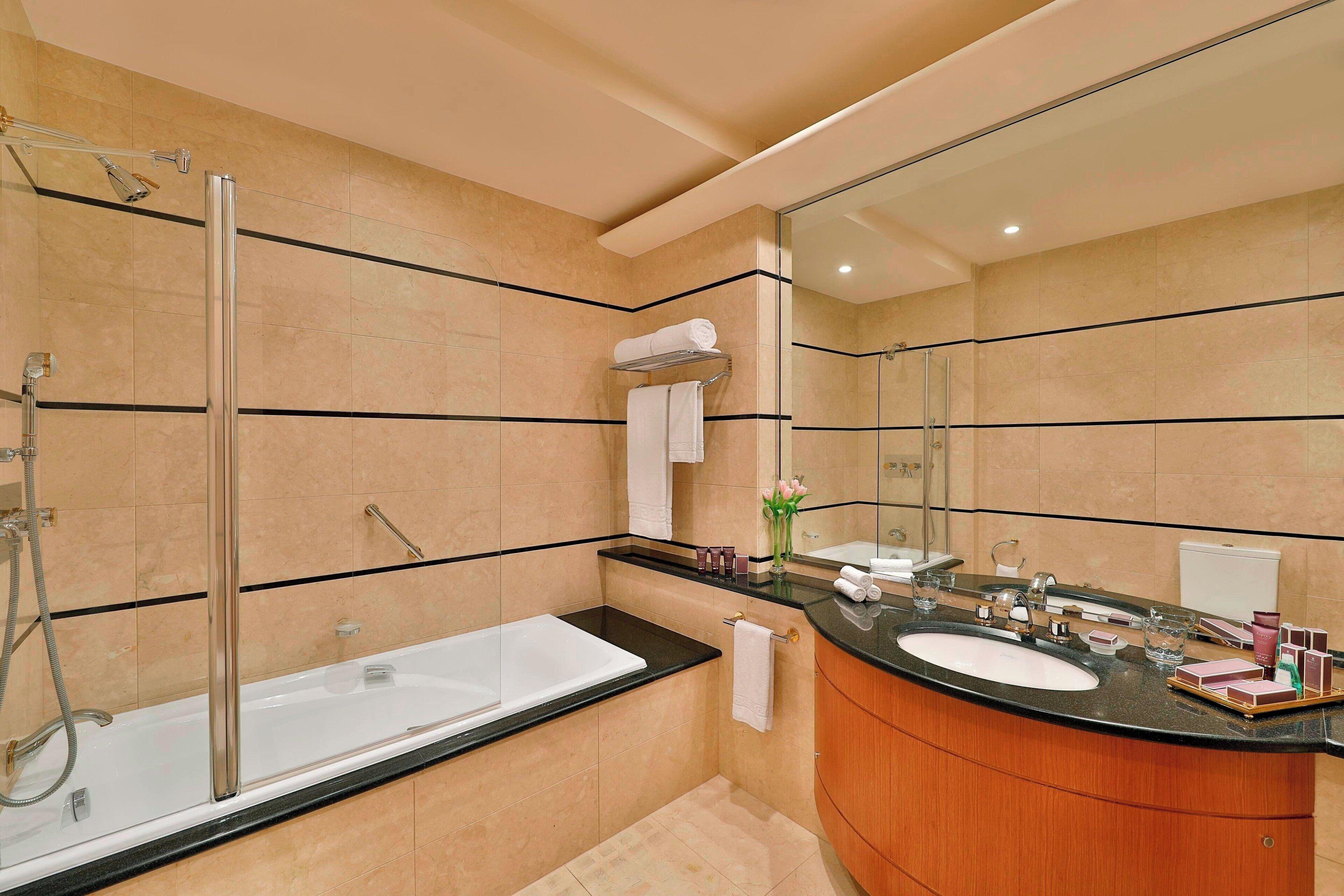 A modern bathroom with a glass-enclosed shower, a freestanding bathtub, a vanity with a sink, and a large mirror.