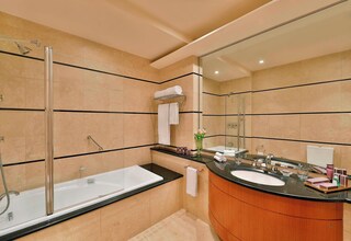 A modern bathroom with a glass-enclosed shower, a freestanding bathtub, a vanity with a sink, and a large mirror.