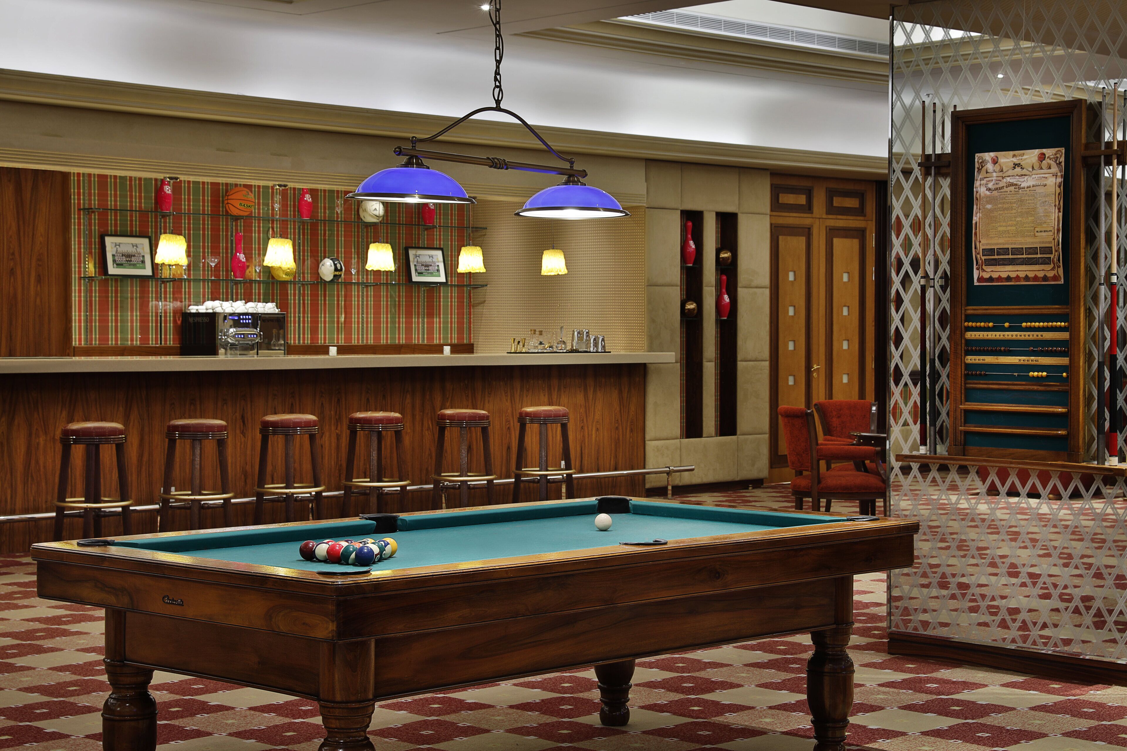 A pool table with balls, a bar area with stools, and a decorative wall with framed pictures.