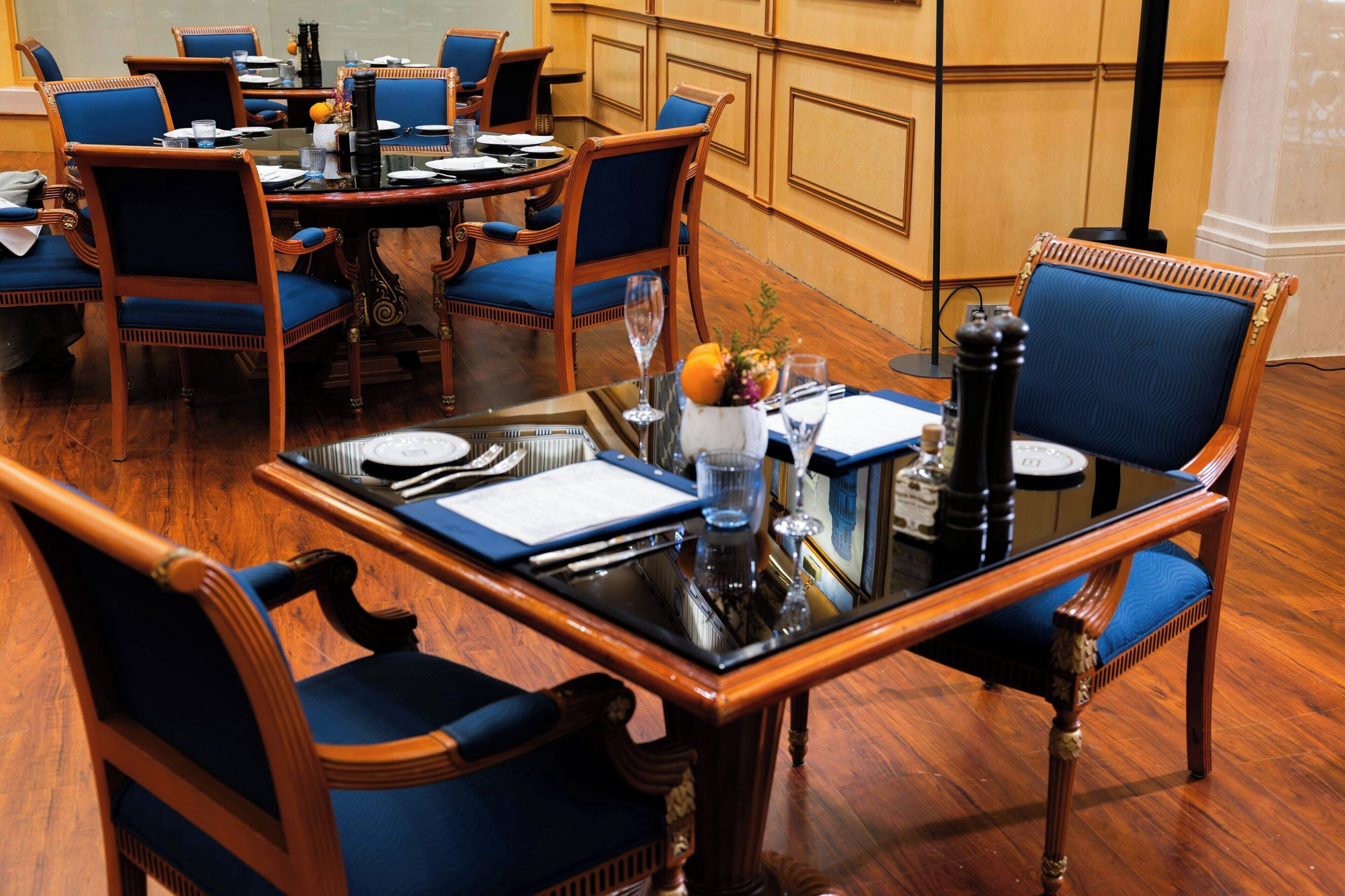 A conference room with a round table, blue upholstered chairs, and a glass-top table.