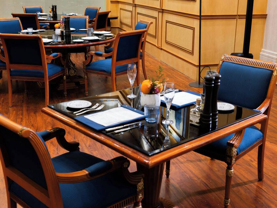 A conference room with a round table, blue upholstered chairs, and a glass-top table.