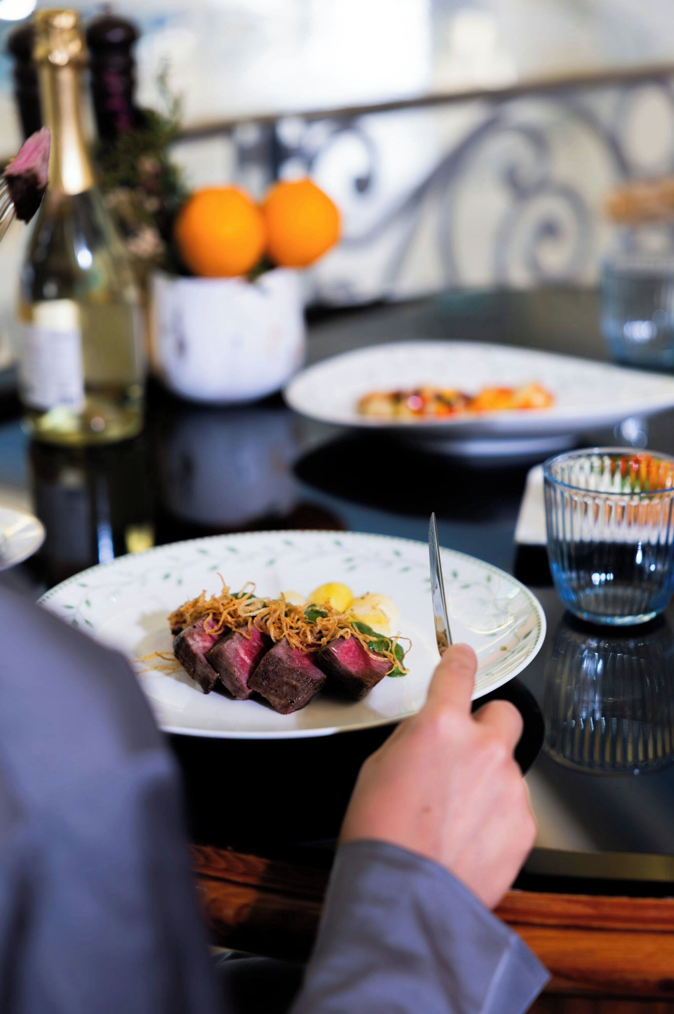 Una mesa de comedor con platos de comida, una botella de vino y un vaso de agua.