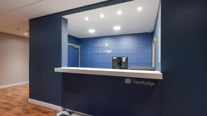 A reception desk with a 'hello & welcome' sign, a water dispenser, and the Travelodge logo. - Travelodge Caernarfon (Caernarfon)