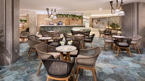 A modern restaurant with wicker chairs and round tables, a counter with a menu, and a decorative wall with plants. - Hotel Riu Buenavista - All Inclusive (Adeje)