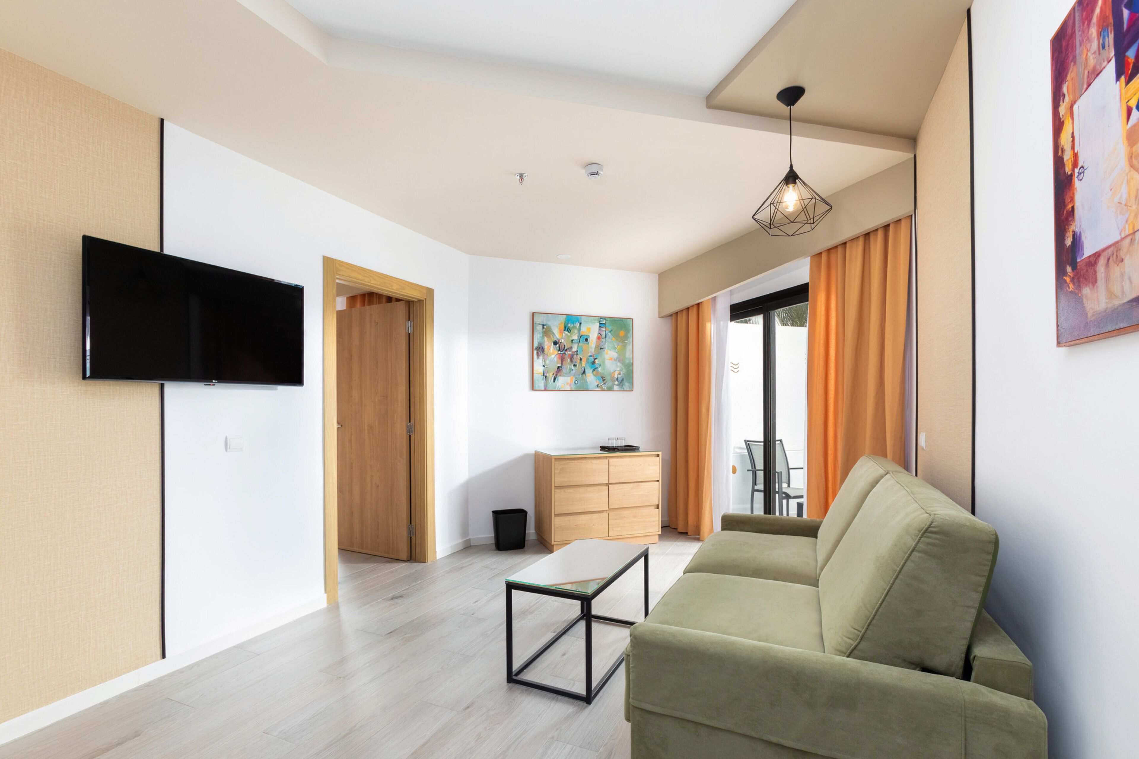 A modern living room with a flat-screen TV, a sofa, a coffee table, and a painting on the wall.