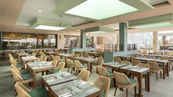 Un restaurant spacieux, doté de nombreuses tables et chaises, de grandes fenêtres et d’un plafond au design moderne.