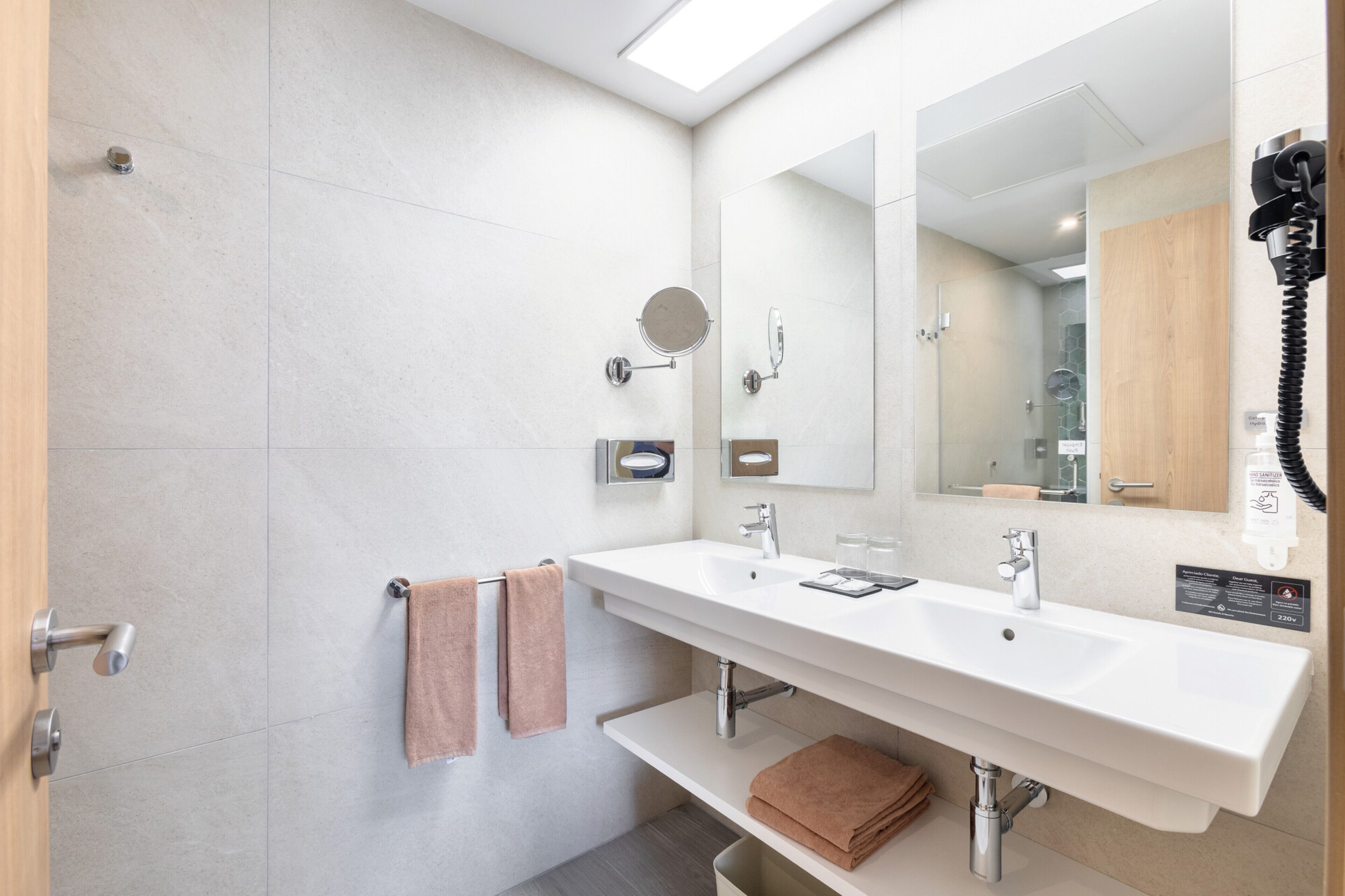 Un baño moderno con un espejo grande, un lavamanos y una zona de ducha.