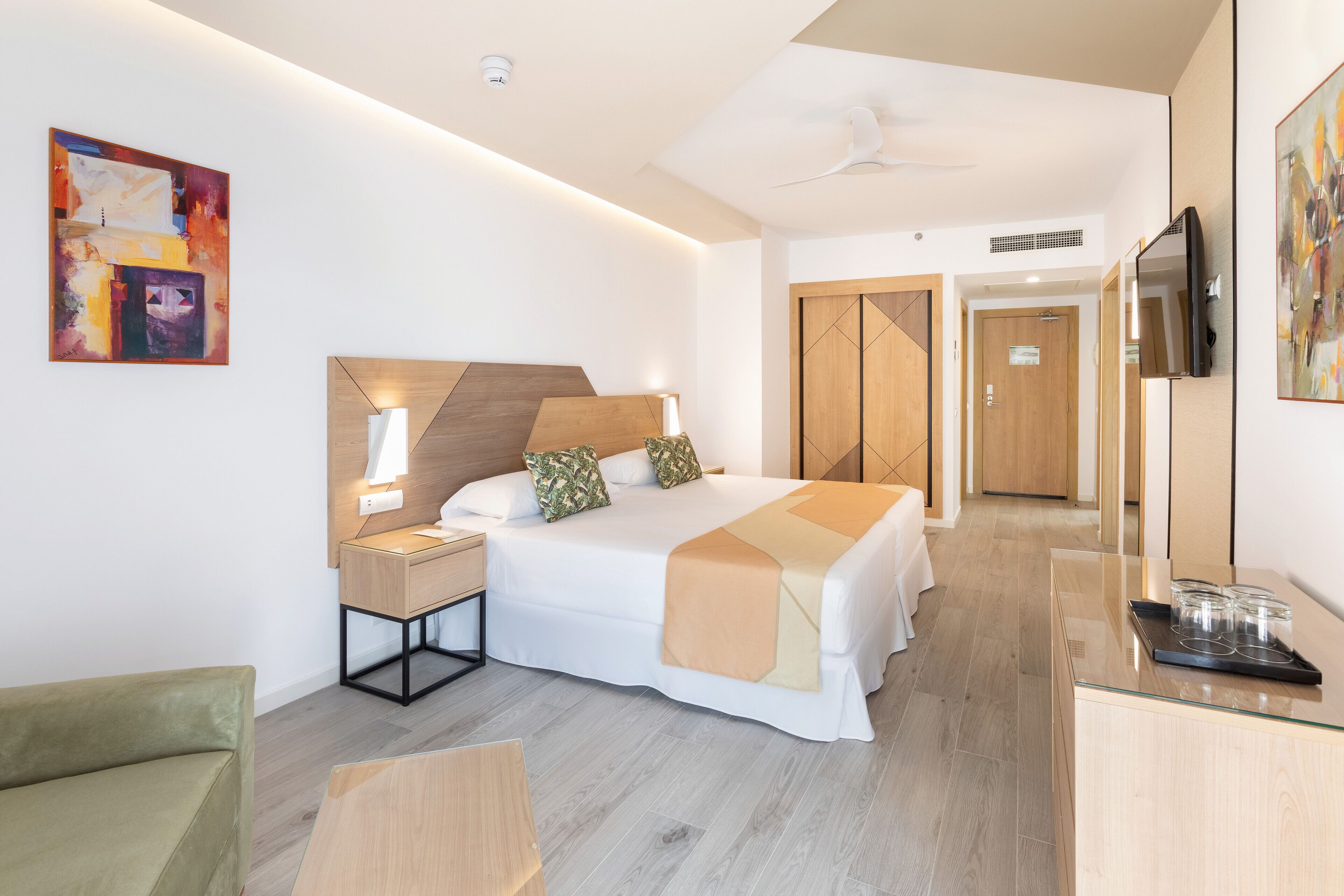 Une chambre d’hôtel moderne équipée d’un lit, d’une table de chevet, d’une lampe et d’un téléviseur.