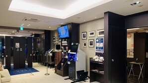 A hotel lobby with a reception desk, a digital information kiosk, and framed pictures on the walls. - Sotetsu Fresa Inn Hamamatsucho Daimon (Tokyo)