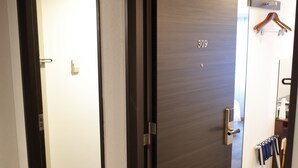 A hotel room with a closed door, a visible room number, and a coat rack with hangers. - Sotetsu Fresa Inn Hamamatsucho Daimon (Tokyo)