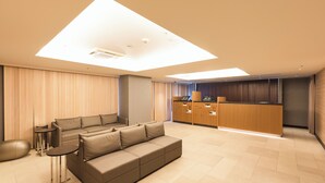 A modern living room with a sofa, a coffee table, and a kitchen area with wooden cabinets and a countertop. - Sotetsu Fresa Inn Tokyo Kyobashi (Tokyo)