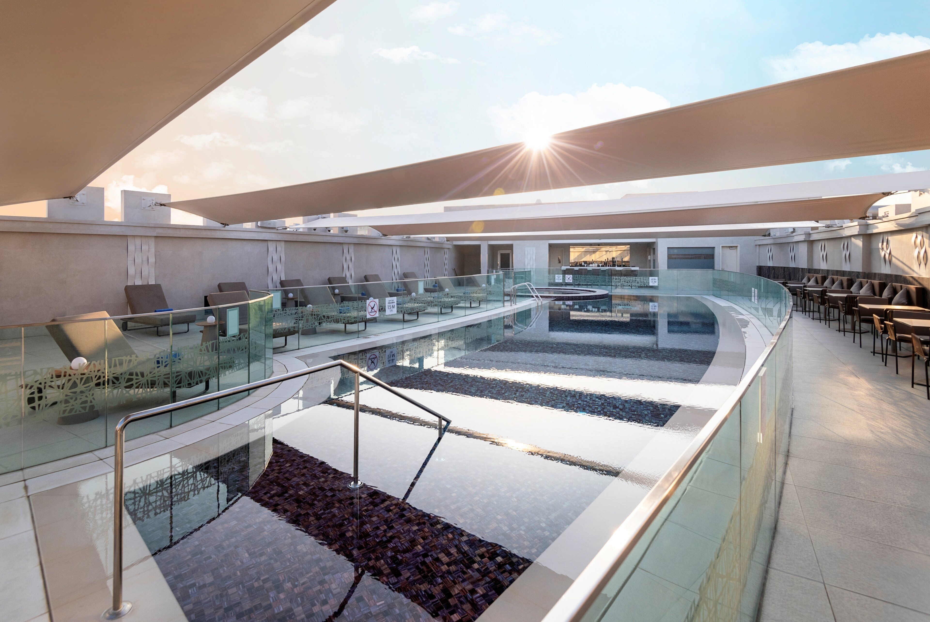 A rooftop terrace with glass railings, seating areas, and a pool.