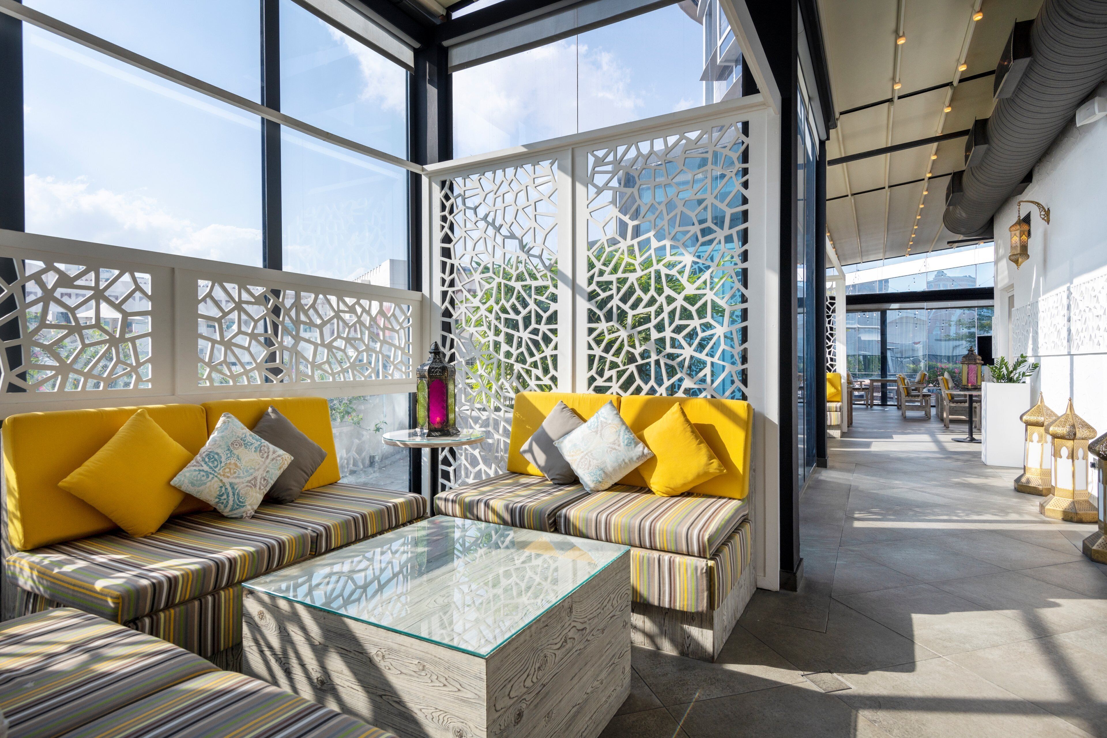 A modern lounge area with a glass coffee table, striped sofas, and decorative lanterns.