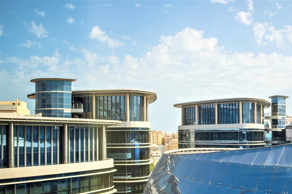 Un bâtiment moderne doté de façades en verre incurvé et d’une installation de panneaux solaires sur le toit.